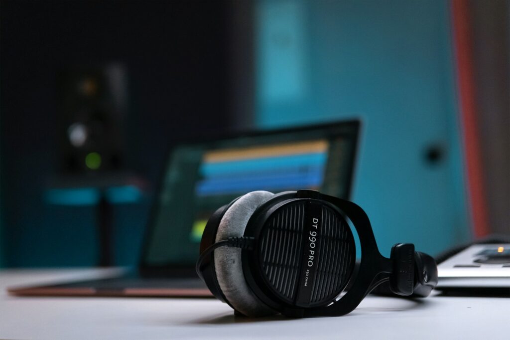 Pair of wired studio headphones resting on a table in dark teal light